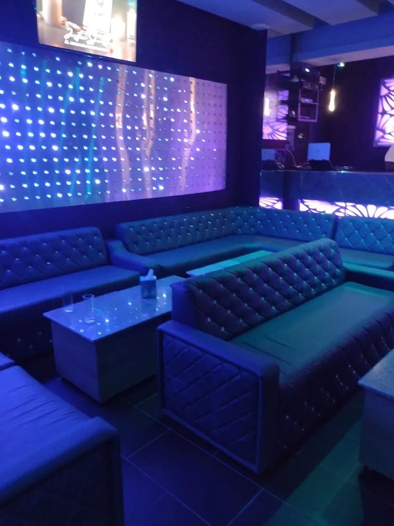 Espace lounge du bar avec banquettes capitonnées et mur lumineux à LED bleues
