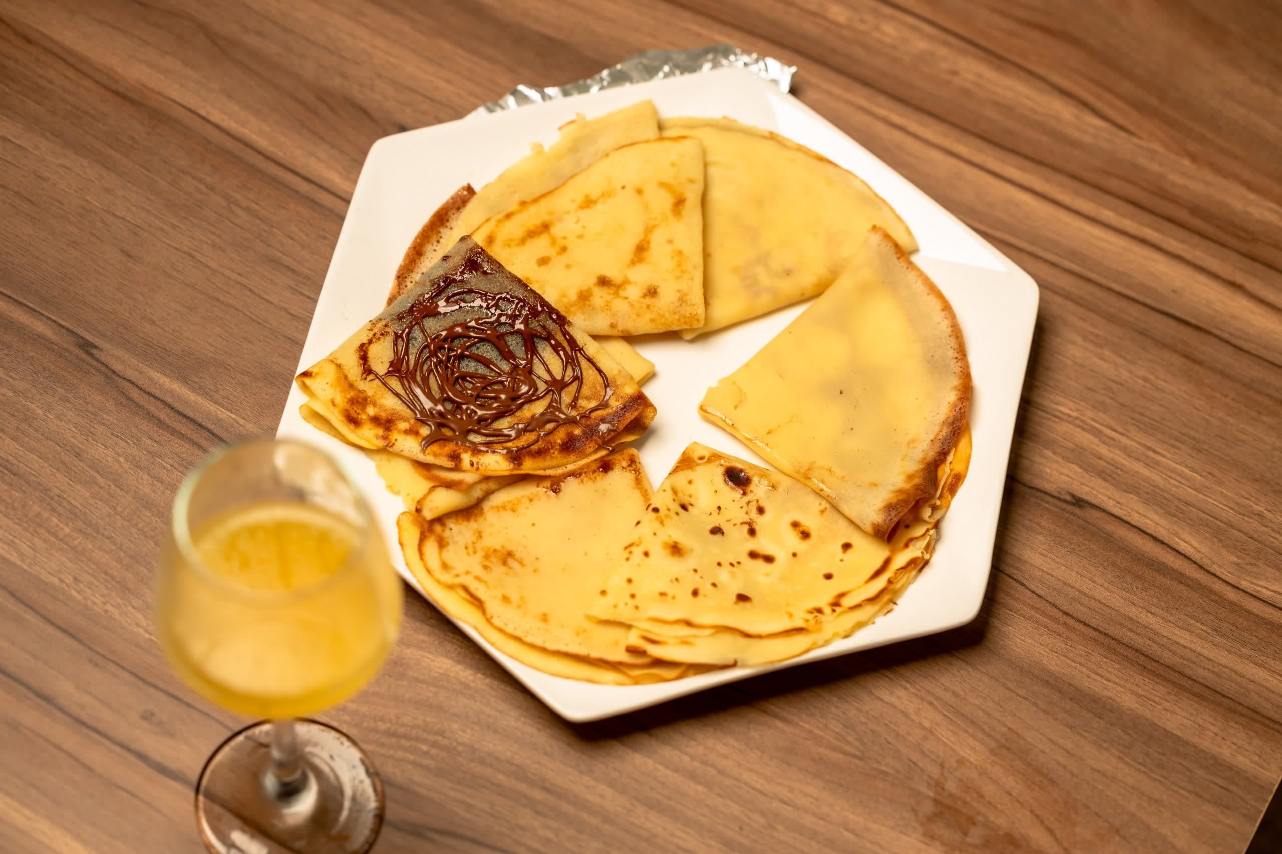 Assiette de crêpes au chocolat et verre de jus au restaurant Délices de Luxe